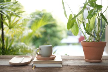 Çay fincanı, defter ve saksı, balkonda.