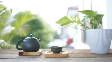 Kaliteli çaydanlık ve çay fincanı dışarıda, ahşap masada.