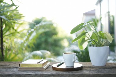 Küçük beyaz bardak ve defter ve dışarı saksı balkonu.