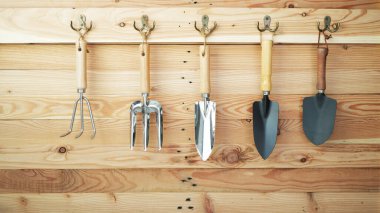 Ahşap duvarda asılı bahçe aletleri.