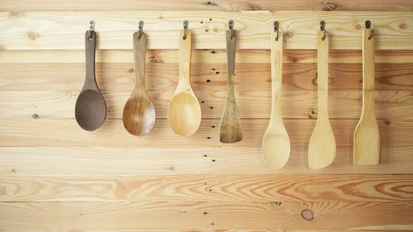 stock image wooden spatula and spoon in different size hanging on wooden wall