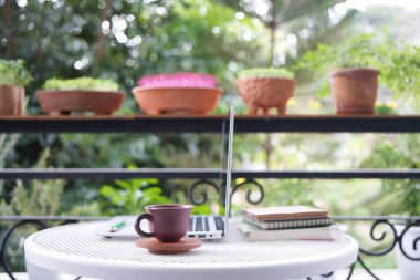 Toprak kap kil kahve fincanı balkonda ve dizüstü bilgisayarın yanında.