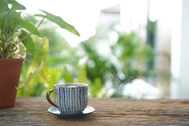 Philodendron kil çaydanlık ile klasik çay fincanı balkon açık havada ahşap masa üzerinde bitki bitki, yavaş yaşam