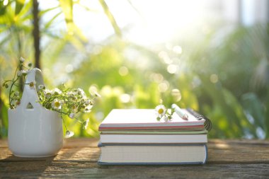 Papatya çiçekleri ve defter ahşap masa üzerinde bahçe manzaralı