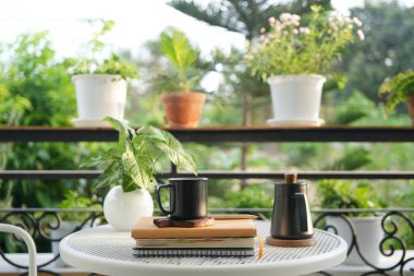 Siyah çaydanlık ve çay fincanı balkondaki metal masada.