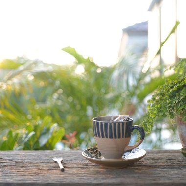 Balkondaki ahşap masada saksısı olan eski toprak çay fincanı, yavaş yaşam.