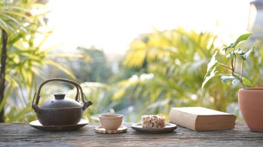 Metal çay demliği ve çay fincanı ve ahşap masada çıtır pirinç kraker, rahat çalışma alanı