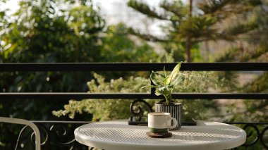 Kahve fincanı, beyaz masa üzerinde demlik, balkon, açık hava.