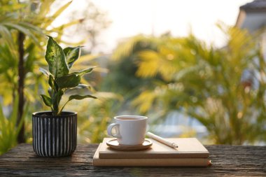 Beyaz kahve fincanı ve defter, açık alanda çalışma alanı.