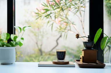 Kahve bardağı, saksı, cam kenarında kahve öğütücüsü.