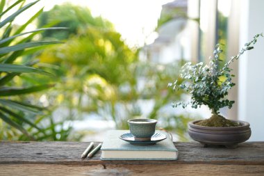 Çay fincanı ve saksısı ve bahçe manzaralı bir defter.