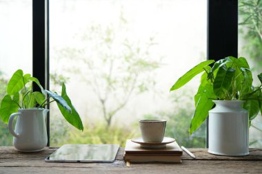 Pencere kenarında saksısı olan toprak takımı çaydanlık ve tablet