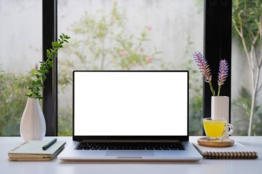 Beyaz ekranlı dizüstü bilgisayar ve ananas suyu ve mor çiçek, kapalı alanda rahat çalışma alanı