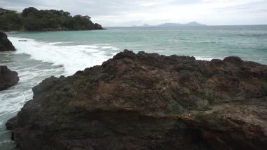Yeni Zelanda 'nın kuzeyindeki Langs Sahili' nde güzel bir sahil manzarası, bulutlar, kayalar ve dalgalar.