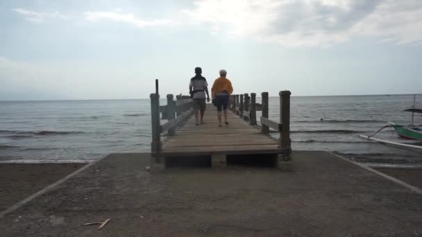 Una Pareja Ancianos Está Caminando Puente Madera Borde Playa Lovina — Vídeos de Stock