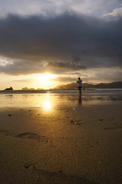 Banyuwangi, Endonezya - 5 Kasım 2020: Turistler Pulau Merah plajında gün batımının tadını çıkarıp oynuyorlar.