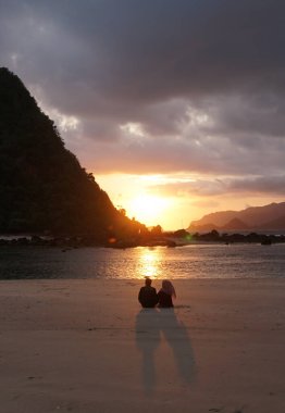 Banyuwangi, Endonezya - 5 Kasım 2020: Turistler Pulau Merah plajında gün batımının tadını çıkarıp oynuyorlar.