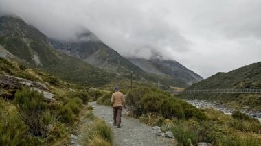 Bir adam Yeni Zelanda 'daki Cook Ulusal Parkı' ndaki fahişe vadisi patikasında yürüyor..