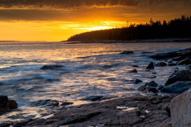 Acadia National Park, ME - USA - Oct. 13, 2021: Sunset view of Ship Harbor at Acadia National Park in the Fall. Sunburst reflecting warm orange and yellow reflections on the surf.