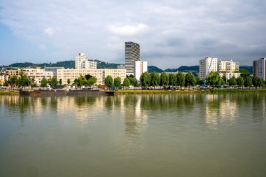 Linz, Yukarı Avusturya - AT - 7 Haziran 2023 Linz ufuk çizgisinin manzarası, Tuna Nehri ön planda.