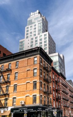 New York, New York - ABD - 16 Eylül 2023 Ludlow ve Stanton caddelerinin köşesi New York 'un Aşağı Doğu Yakası. Eski tuğla konutlar ve modern çelik ve cam lüks otel Indigo Aşağı Doğu Sidw arasındaki zıtlık