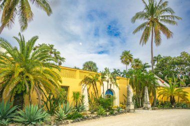 Fort Lauderdale, FL - ABD - 7 Şubat 2024 Capnet House 'a girişin peyzaj manzarası, canlı çiçekler ve yemyeşil yeşilliklerle bezenmiş yemyeşil bir tropik cennetin ortasında duran tarihi bir ev müzesi.