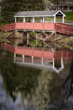 Mahwah, NJ - US- 14 Nisan 2024 Mahwahs Kış Parkı 'ndaki sakin Winters Pond' daki yansımaların güzel ahşap bir köprüsü var.