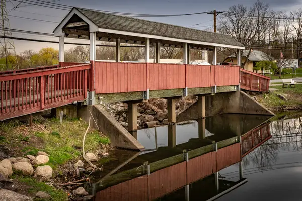 stock image Mahwah, NJ - US- Apr 14, 2024 Landscape view of reflections in the serene Winters Pond in Mahwahs Winters Park, with a beautiful wooden covered bridge