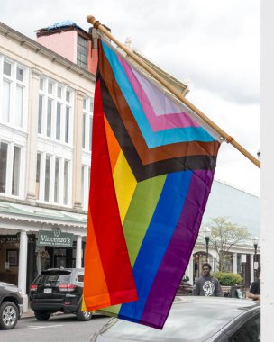 Kingston, NY - US - May 11, 2024 2018 Vertical closeup view of the inclusive Progress Pride Flag, designed by Daniel Quasar. Hanging in front of the Hudson Valley LGBTQ+ Community Center in Kingston. clipart