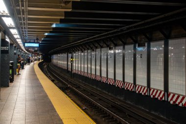 New York, New York, New York 7 Haziran 2024 Whitewall St South Ferry metro istasyonunda bir sonraki R trenini beklerken, şehir ulaşımının ritmiyle çalkalanıyor.