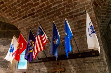 Bronx, NY - US - Aug 24, 2024 The chapel at Fort Schuyler features a vaulted brick ceiling and a row of military flags, including the U.S. flag, symbolizing honor and patriotism. clipart