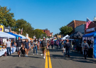 Suffern, NY - US - Sep 15, 2024 The Suffern Street Fair features vibrant vendor booths lining both sides of the street, with people shopping for crafts and food under sunny skies clipart