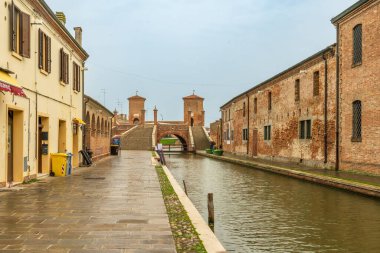 Comacchio, Ferrara  IT  Oct 16, 2024 This canal in Comacchio leads to the iconic Trepponti bridge, a historic landmark with five staircases and arches, showcasing the towns Venetian-style charm clipart