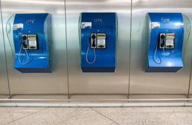 Attiki Odos, Spata - GR - 27 Ekim 2024 Atina Havalimanı 'ndaki OTE markalı ankesörlü telefon, metalik bir duvara monte edilerek klasik bir iletişim seçeneği sunuluyor..