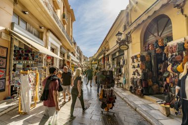 Atina, Attica - GR - 25 Ekim 2024 Atina, Plaka 'da canlı bir cadde, dükkanlar, el yapımı mallar ve bu tarihi bölgenin cazibesini yakalayan sıcak güneşin altında gezinen turistlerle dolu..