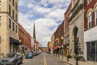 Middletown, New York - ABD - 1. Mar, 2025 Kuzey Caddesi, Middletown, New York 'ta, tarihi tuğla binalar, trafik ışıkları, vitrinler, arabalar ve arka planda parçalı bulutlu bir gökyüzünün altında uzun bir çan kulesi.