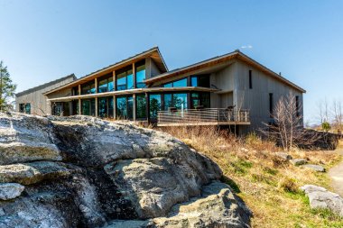 Kerhonkson, New York - ABD - 23 Nisan 2025 Modern, ahşap kaplı Minnewaska Eyalet Parkı karşılama merkezi büyük cam pencereli taş çıkıntılarının yanında duruyor, açık bir gökyüzü altında doğal ortama karışıyor..