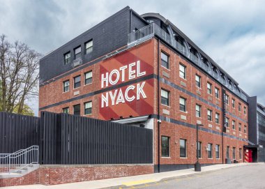 Nyack, New York - ABD - 27 Nisan 2025 Moda Oteli Nyack modern endüstriyel tasarımı ile dimdik ayakta duruyor, kırmızı tuğla duvarlar, siyah aksanlar ve bulutlu bir gökyüzü altında koyu beyaz harfler..