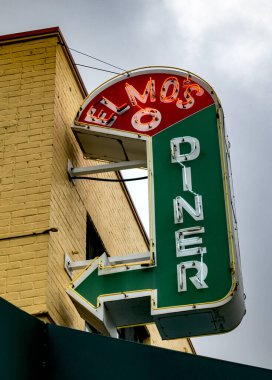 Durham, NC - ABD - 4 Mayıs 2025 Elmo 'nun Lokantası tabelası bulutlu bir gökyüzüne karşı parlıyor, sarı tuğla bir binaya monte edilmiş, koyu yeşil bir ok klasik konforlu yiyecekleri işaret ediyor..