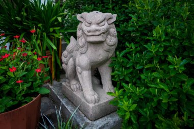 Yonkers, New York - ABD 8 Haziran 2025 Görkemli bir Foo Dog heykeli Untermyers Duvarlı Bahçesi 'nde nöbet tutuyor, yemyeşil bitki örtüsü tarafından çerçevelenmiş, efsanevi varlığını ve zamansız zarafetini artırıyor.