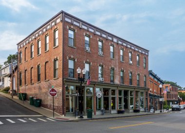 Beacon, New York - ABD 13 Haziran 2025 Beacon, New York 'taki ana caddede eski usul üç katlı tuğla bir bina altında büyüleyici mağazalar ve yukarıda klasik pencereler, küçük kasaba mirasını yansıtıyor..