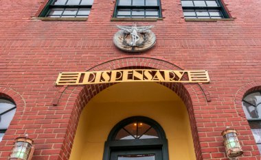 Beacon, NY - US - Jun 13, 2025 The Station Dispensary in Beacon, NY: A brick building with arched entry, twin windows, and a winged emblem above a bold DISPENSARY sign
