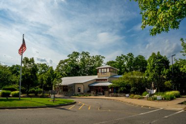 Sefer, New York - ABD - 21 Haziran 2025 Izdırap çeken Özgür Kütüphane girişi bir güneş saati heykeli, bereketli bir peyzaj ve taştan duvarları ve mavi gökyüzünün altında kırmızı çerçeveli pencereleri olan kırsal bir bina içeriyor..