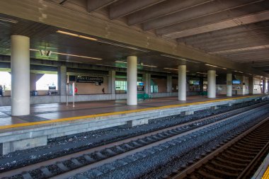 Secaucus, NJ - ABD - 6 Haziran 2025 Secaucus kavşağının alt katında modern bir üst geçidin altında geniş platformlar, beton sütunlar ve parlak tabelalar bulunmaktadır..