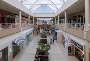 Middletown, New York - ABD - 9 Ağustos 2025 Crystal Run 'daki Galleria' nın iki katlı iç kesimi, ağaçlarla kaplı merkez geçidi, parlak gökyüzü tavanı ve geniş alışveriş merkezini keşfeden müşteriler.