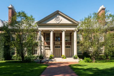 Deerfield, MA - ABD - 23 Ağustos 2025 Deerfield Akademisi 'nin Sütunlu Ana Okul Binası, Charles A. Platt tarafından saat yüzlü, yeşil çimenler ve ağaçlarla çevrili, açık mavi gökyüzü altında.