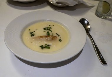 Bu kaymak gibi soğuk çorba güzel bir şekilde sunulur, taze otlarla süslenir ve lezzetli bir parça balık sunulur, enfes bir aşçılık deneyimi sunar..