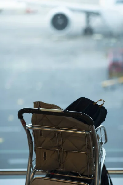 luggage on a trolley at an airport in the background a waiting plane. Selective focus