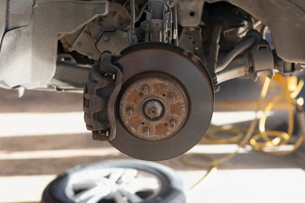 Car being serviced on lift deck, brake discs in foreground. Selective focus