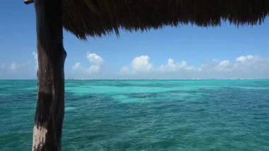 Meksika 'daki Mujeres Adası' ndaki ahşap bir kulübeden Karayip Denizi 'nin panoramik manzarası. Thatched çatı, şeffaf sular, uzak kıyı şeridi, ve mavi gökyüzü - dinlenmek için harika bir yer..